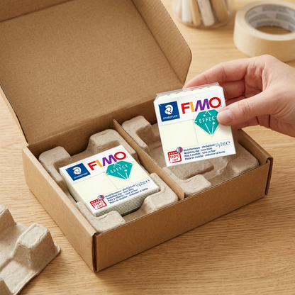 A premium, close-up photograph of hands gently unboxing genuine STAEDTLER FIMO Effect Noctilucent clay from protective transit packaging.