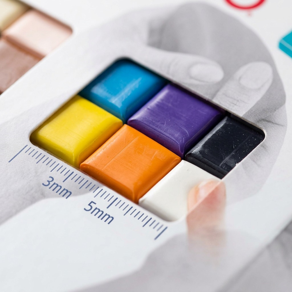 Extreme macro view of the 30-color STAEDTLER FIMO Soft block set, showing the detailed layout, specific colors, and embossed block texture through the original packaging windows, emphasizing the variety, premium material quality, and print detail without any text or logos on the product itself.