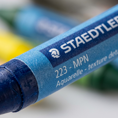 Macro close-up of dark blue Staedtler watercolour crayon, showing waxy pigment texture and paper label details.
