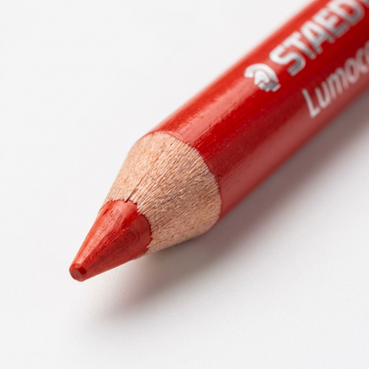 Macro detail of the red wax tip and wooden sharpening cone of the STAEDTLER glasochrom dry marker.