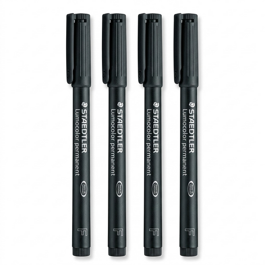 High-resolution macro photograph of four black Staedtler Lumocolor permanent markers, upright on a white background.