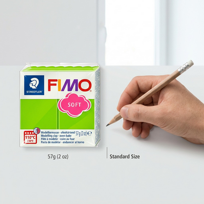 STAEDTLER Fimo Soft block with hand holding a pencil for scale on a light grey surface.