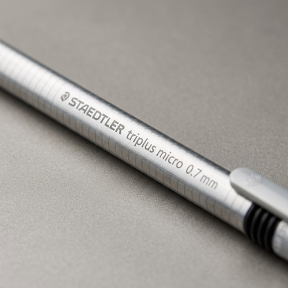 Macro close-up of STAEDTLER triplus micro pencil barrel, focusing on precision text and grip texture.