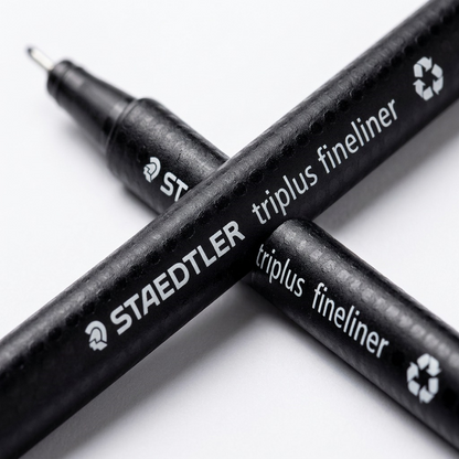 Macro detail shot focuses on the printed text and barrel texture of the black Staedtler fineliner.