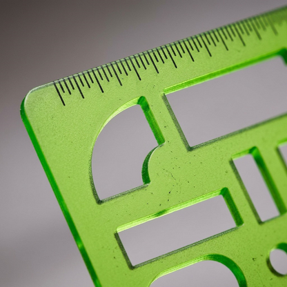 An extreme macro shot showing the fine millimeter ruler and sofa cutouts on the STAEDTLER home furnishing template.