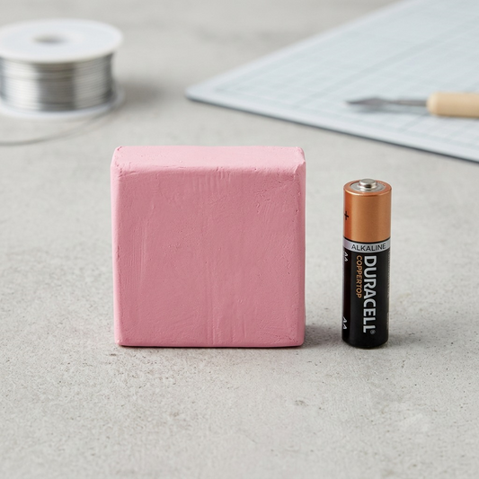 A clean, product-led image showing the STAEDTLER Fimo Effect Rose Quartz clay block next to a standard AA battery.