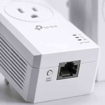Extreme close-up of a TP-Link powerline adapter's Gigabit Ethernet port, status LEDs, and side vents with a reset button.