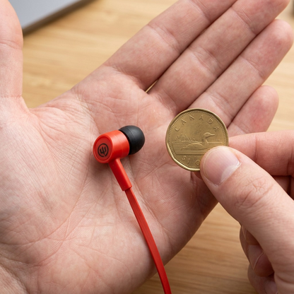 A Wicked Audio HavoK earbud rests on a hand, comparing its true size to a person's thumb.