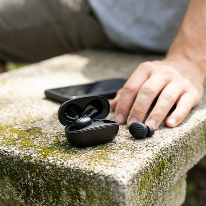 A person wearing a Wicked Audio Mojo 300 TWS in-ear while using their smartphone. The image shows the true wireless earbud resting securely in their ear, highlighting its ergonomic design and discreet placement. The focus is on the earbud itself, with the surrounding elements such as the phone and background lightly blurred. The scenario represents a user on an average daily commute. No packaging, text, or logos.