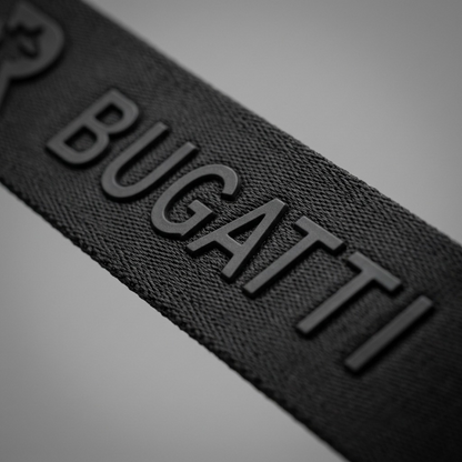Macro close-up of the Bugatti Reborn grey crossbody bag showing embossed logo on durable RPET fabric.