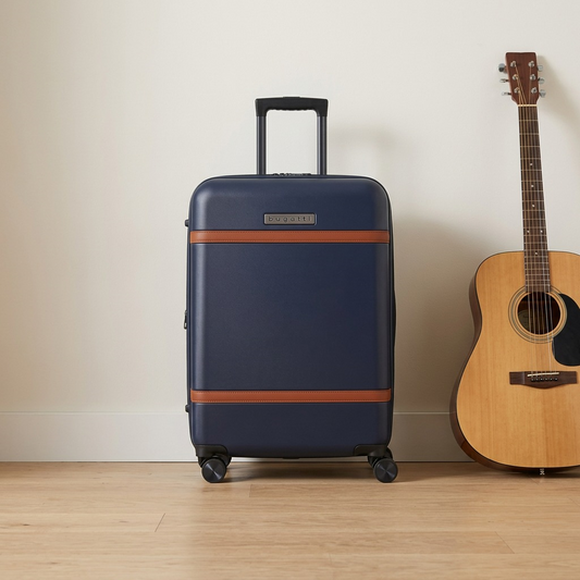 Navy Bugatti Wellington 24-inch luggage standing next to an acoustic guitar for scale reference.