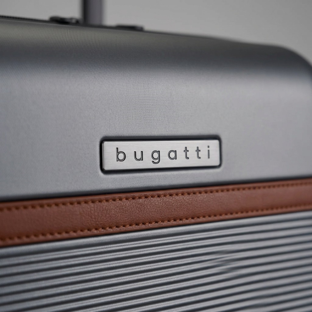 Macro detail of Bugatti Wellington luggage showing the metal logo plate and vegan leather trim.
