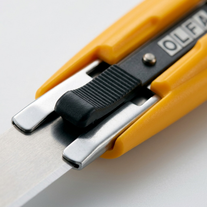 Macro detail of the Olfa SK-9 safety knife's textured slider and steel blade guide.
