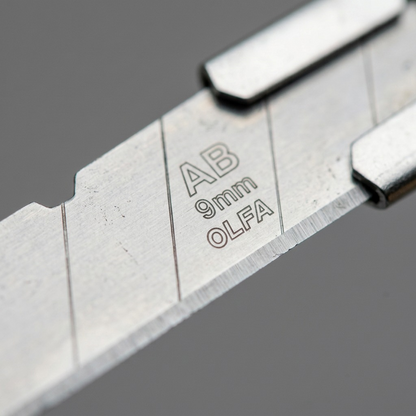 Extreme macro view of the original etched text on the silver steel snap-off utility blade.