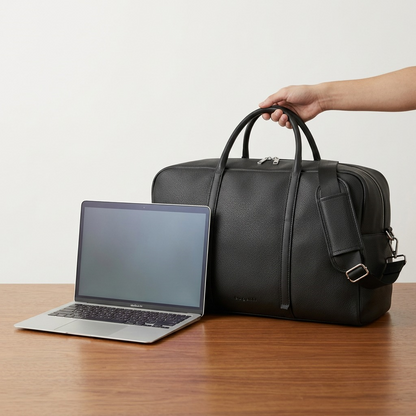 Black Bugatti Opera duffle bag shown next to a laptop for scale on a wooden desk.