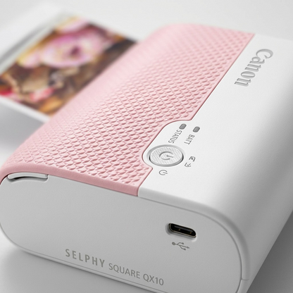 Macro shot of pink SELPHY QX10 printer, highlighting control buttons, charging port and textured surface.